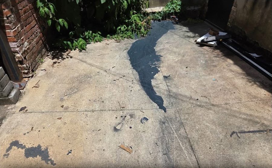 Oil-stained concrete patio before pressure washing